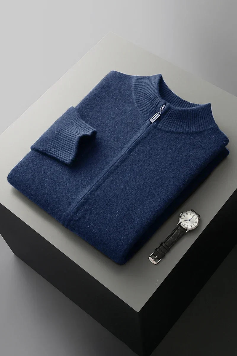 Blå uldtrøje med lynlås, foldet på grå overflade ved siden af et elegant armbåndsur. Stilfuldt herretøj, moderne design, luksusmode.