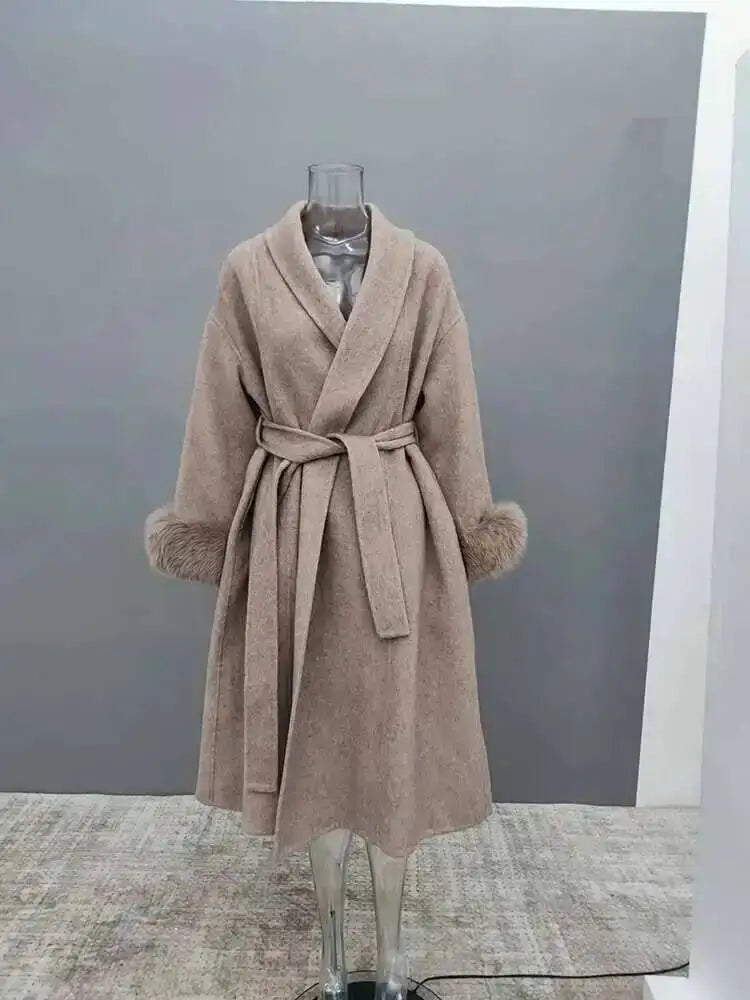 Beige uldfrakke med bælte og pelsmanchetter på gennemsigtig mannequin. Elegant vintermode, stilfuld overtøj til kvinder.