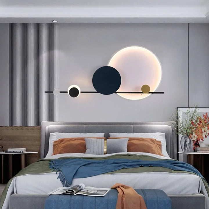 Moderne soveværelse med stilfuld vægdekoration af cirkler, grå polstret seng, farverige puder og sengetæppe. Elegant indretning, minimalistisk design.