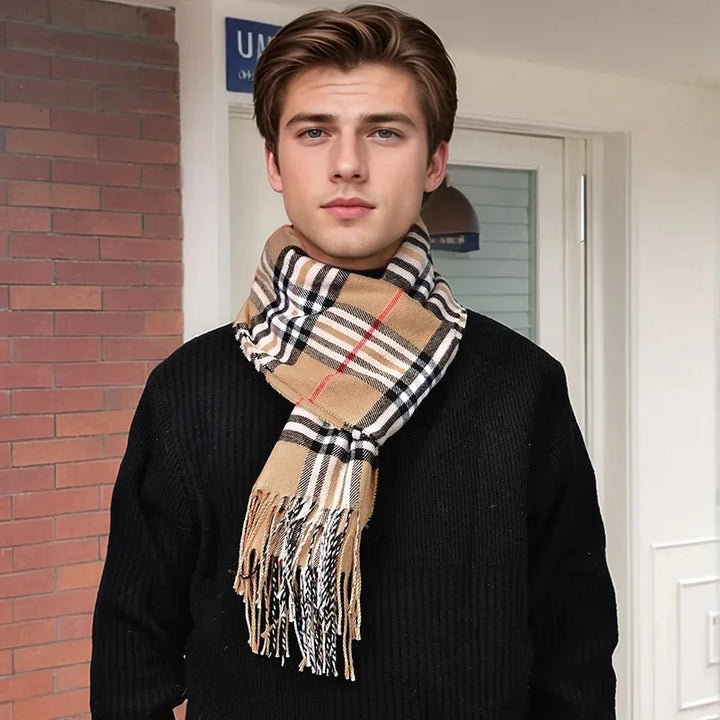 Ung mand iført en ternet Burberry-inspireret halstørklæde og sort sweater foran murstensvæg. Mode, vintertilbehør, stilfuldt look.