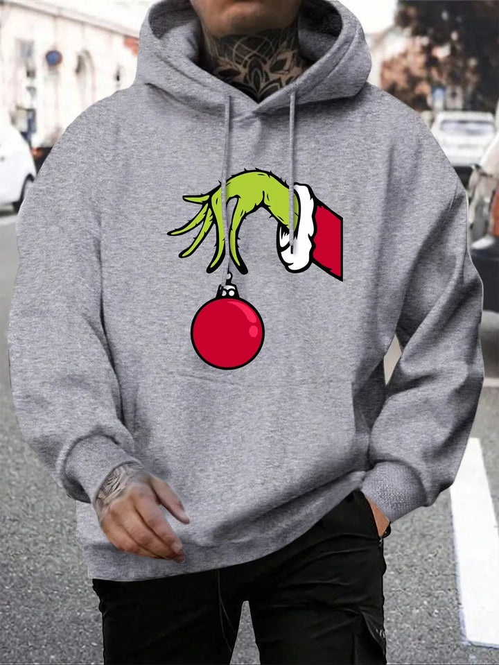 Grå hættetrøje med Grinch-hånd, der holder en rød julekugle. Perfekt til jul, unisex design, streetwear stil.