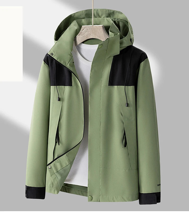 Grøn herrejakke med hætte og sorte detaljer, hængende på bøjle. Moderne design, velegnet til udendørs brug. Vindtæt og vandafvisende.
