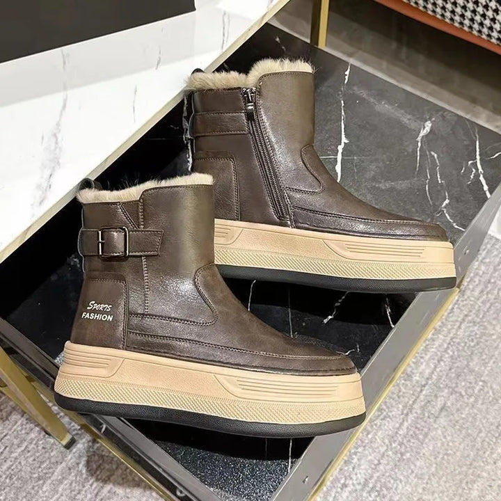 Brune vinterstøvler med pelsfor, lynlås og spænde, placeret på marmorbord. Moderne design, komfortable og stilfulde sko til koldt vejr.