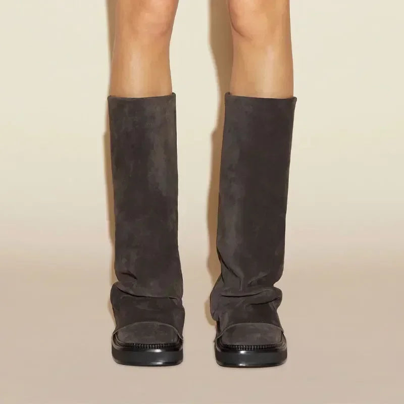 Brune ruskindsstøvler med flad sål, set forfra. Moderne design, knæhøjde, perfekt til efterårsmode. Komfortable og stilfulde støvler til kvinder.