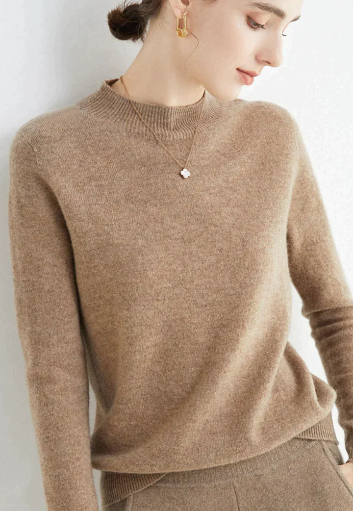 Kvinde iført beige cashmere sweater, elegant design, minimalistisk stil, gyldne øreringe, afslappet mode, luksuriøst tøj, efterårslook.