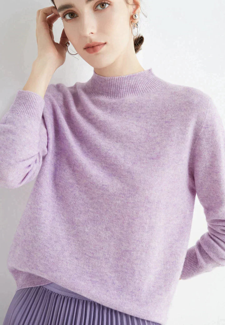 Kvinde iført lys lilla sweater og matchende nederdel, poserer mod hvid baggrund. Elegant mode, minimalistisk stil, pastelfarver, moderne kvindetøj.