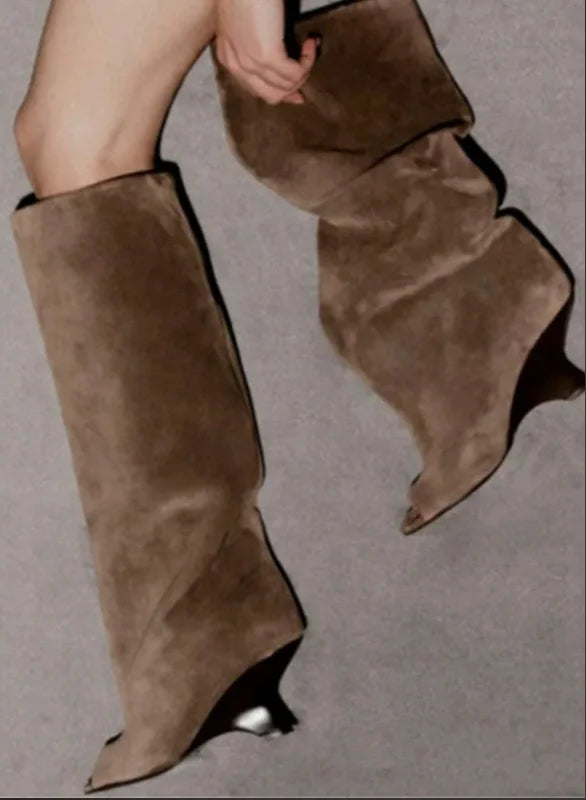 Brune ruskindsstøvler med høj hæl og spids tå på grå baggrund. Moderne fodtøj, stilfuldt design, mode til kvinder.