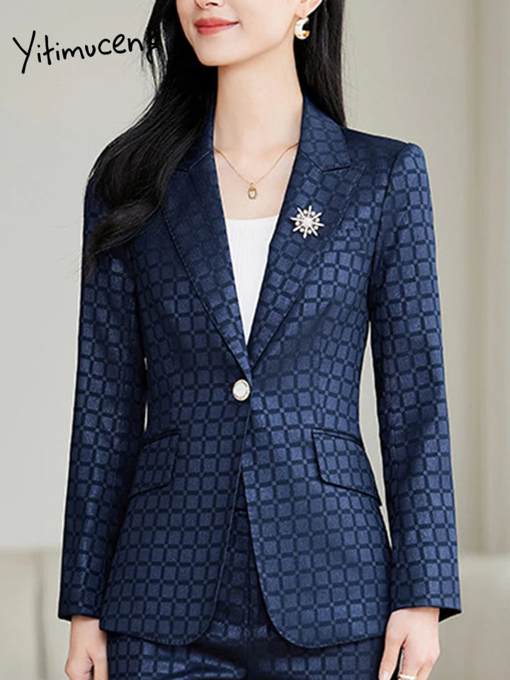 Kvinde i elegant, mørkeblå ternet blazer med guldknap og stjerneformet broche. Perfekt til business eller formelle lejligheder.