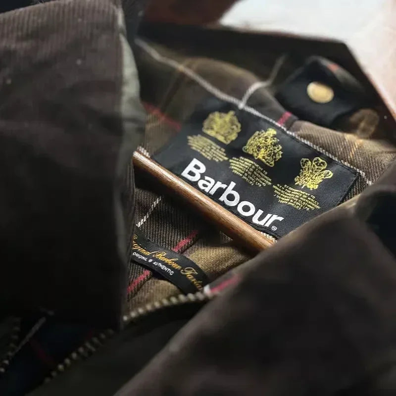 Barbour jakke med tartanmønster og mærkeetiket, klassisk britisk design, slidstærk og stilfuld overtøj til udendørs brug.