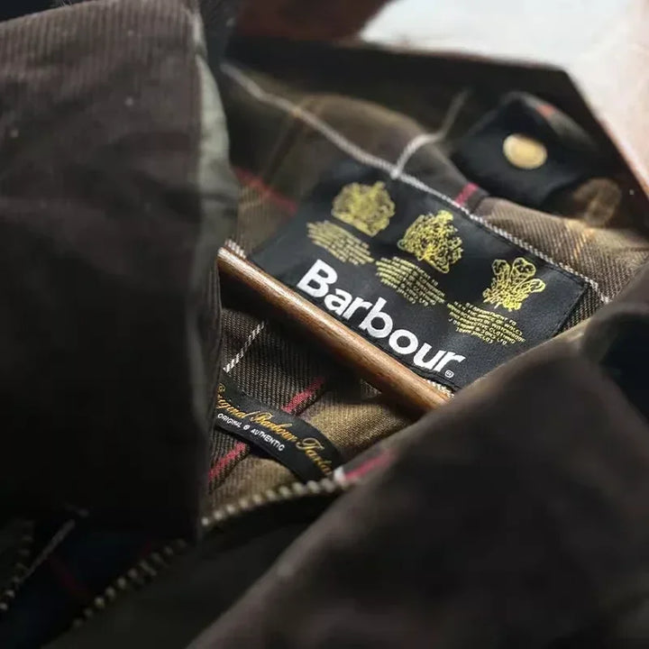 Barbour jakke med tartanmønster og mærkeetiket, klassisk britisk design, slidstærk og stilfuld overtøj til udendørs brug.