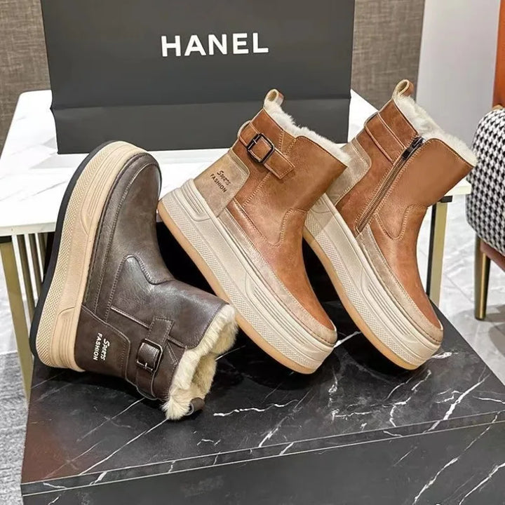 Brune vinterstøvler med pelsfor, lynlås og spænde på sort marmorbord, Hanel shoppingpose i baggrunden. Varmt fodtøj til vintermode.