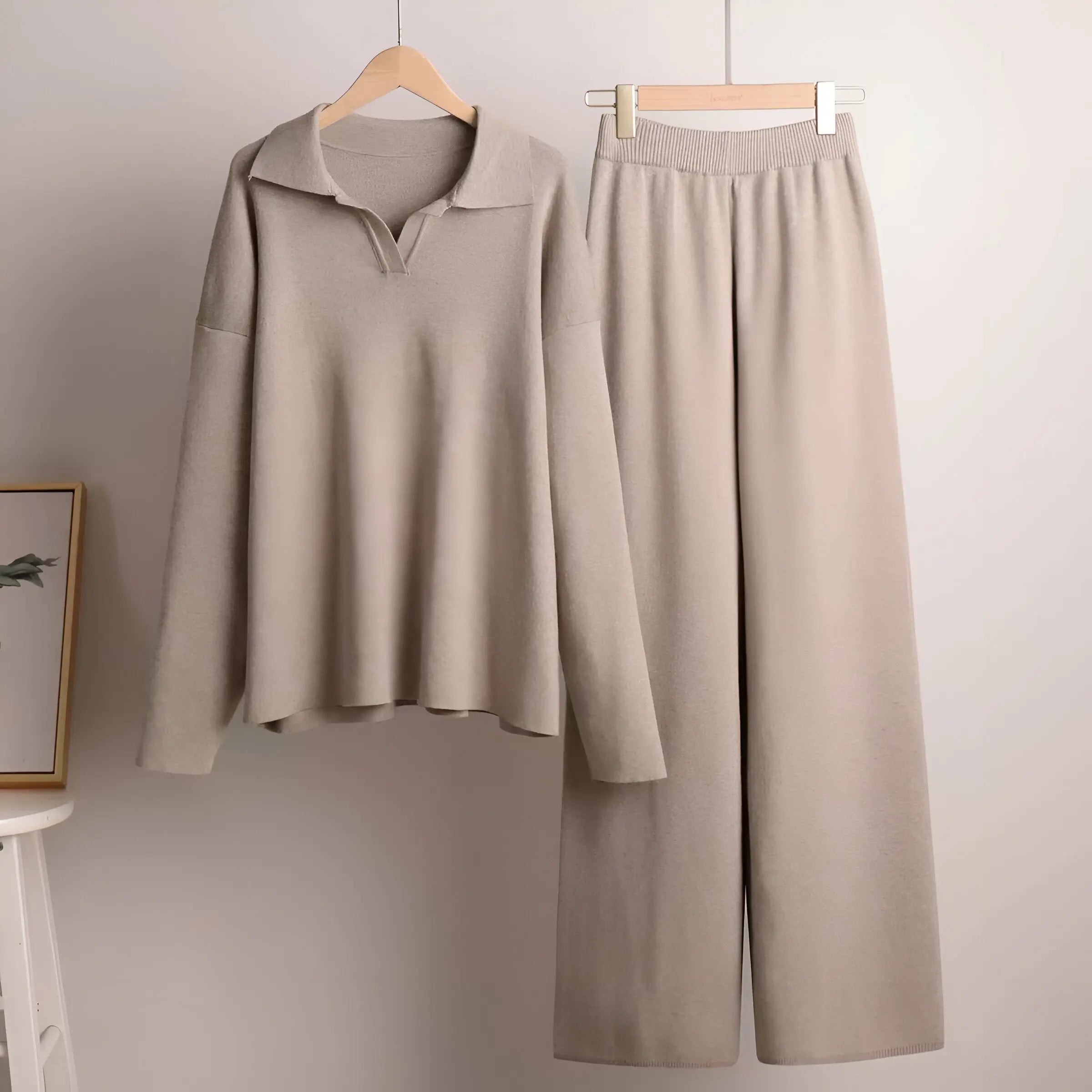 Beige loungewear sæt med langærmet trøje og brede bukser på bøjler. Komfortabelt og stilfuldt tøj til afslapning derhjemme.