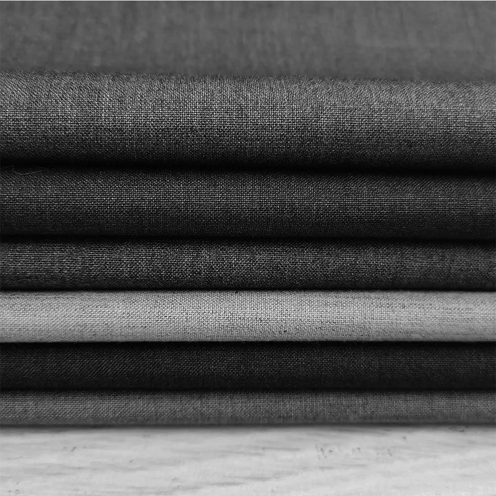 Stabel af grå tekstiler i forskellige nuancer, tæt vævet stof, minimalistisk design, ideel til boligindretning og modeprojekter.