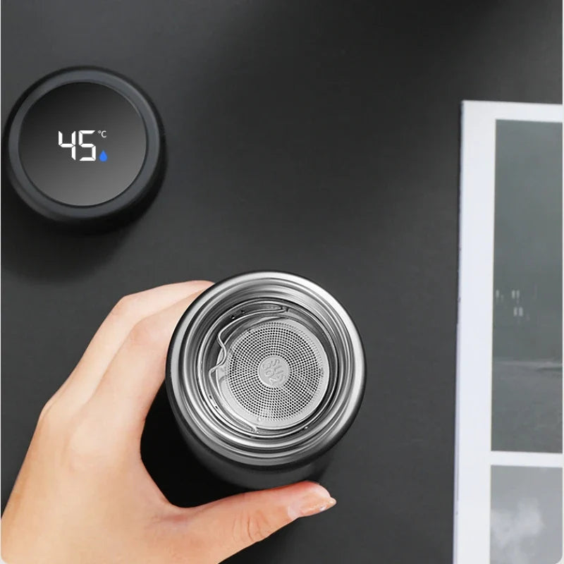Hånd holder sort termoflaske med digital temperaturvisning på 45°C, moderne design, ideel til varm drik, termokop, smart teknologi.