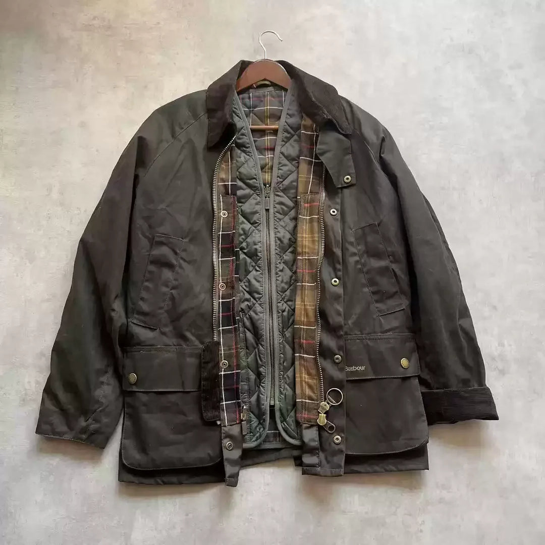Brun Barbour jakke med ternet foring, hængende på bøjle. Klassisk voksjakke, velegnet til udendørs brug. Populær herrejakke i tidløst design.