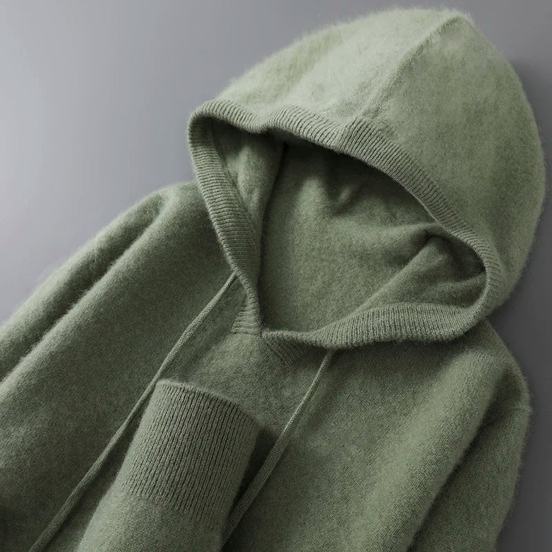 Grøn hættetrøje i blødt uldmateriale, set fra oven. Komfortabelt design med justerbare snore og ribstrikkede manchetter. Perfekt til efterår og vinter.