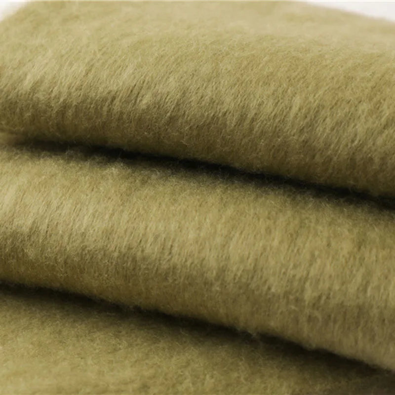 Grøn uldstof i tæt tekstur, stablet i lag. Blødt og varmt materiale til tøjproduktion. Perfekt til vinterbeklædning og håndarbejde.