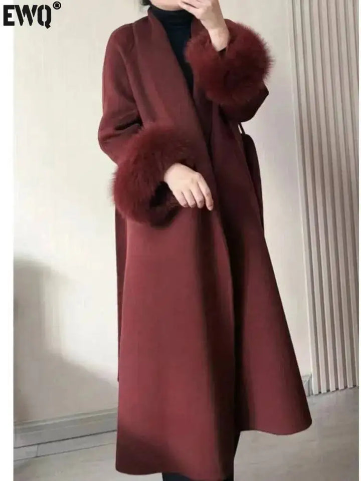 Lang, brun frakke med pelsmanchetter, elegant design, vintermode, kvindetøj, stilfuld overtøj, moderne damefrakke, varm og luksuriøs.