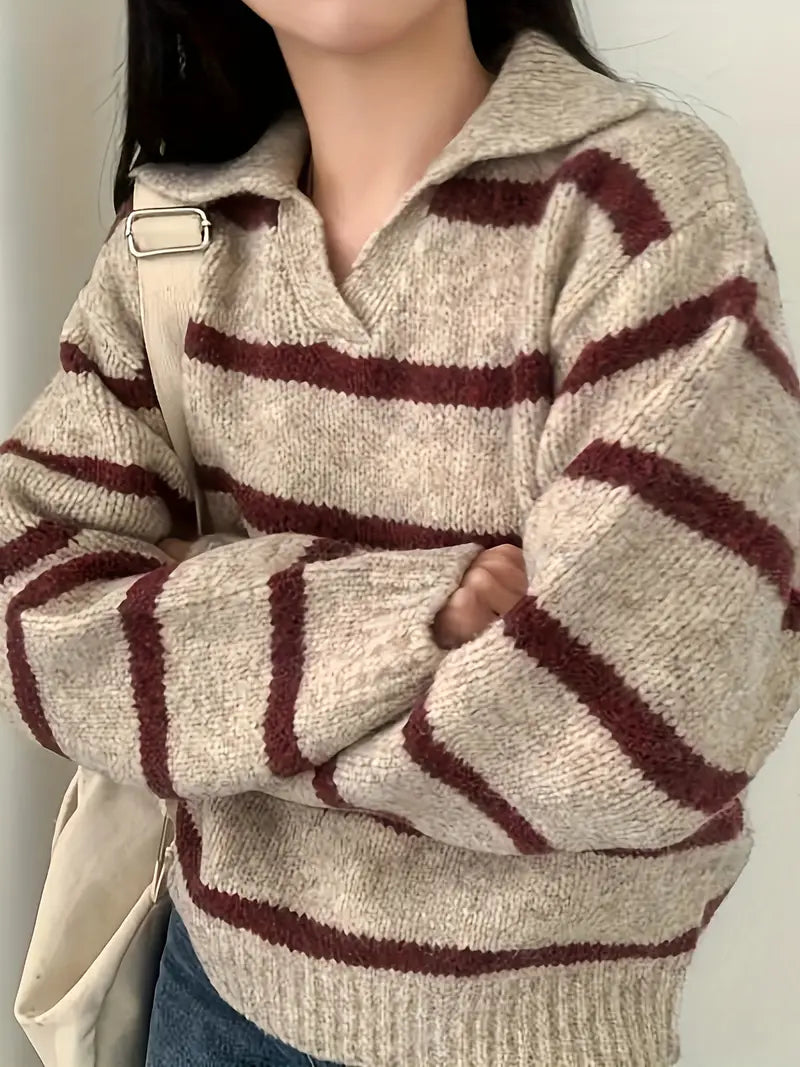 Kvinde iført stribet sweater i beige og bordeaux, med foldede arme. Casual mode, efterårstøj, striktrøje, trendy stil, afslappet look.