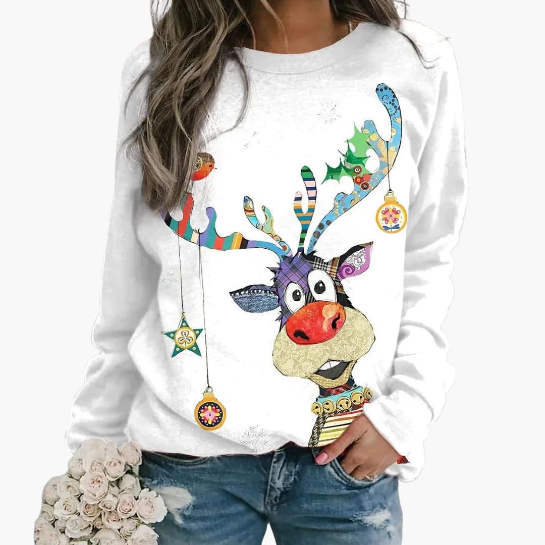 Kvinde iført hvid sweatshirt med farverigt rensdyrmotiv og julepynt, holder en buket blomster. Casual vintermode, juletrøje, festligt design.