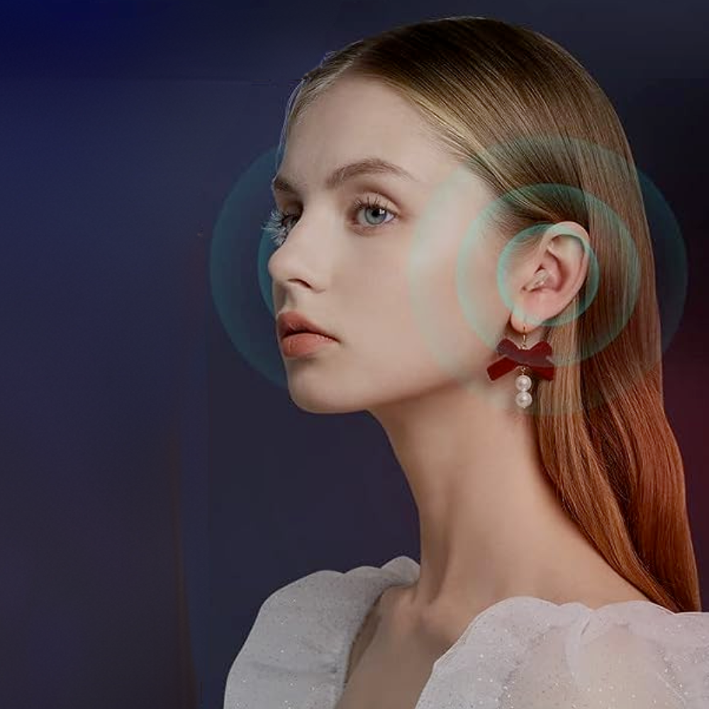 Ung kvinde med langt, glat hår og perleøreringe, iført hvid bluse. Fokus på ansigt og ører, med blå baggrund. Elegant og stilfuldt portræt.