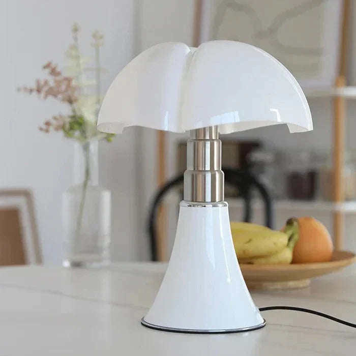 Hvid bordlampe med moderne design på et bord, omgivet af frugt. Stilfuld belysning, indretning, minimalistisk lampe, skandinavisk design.