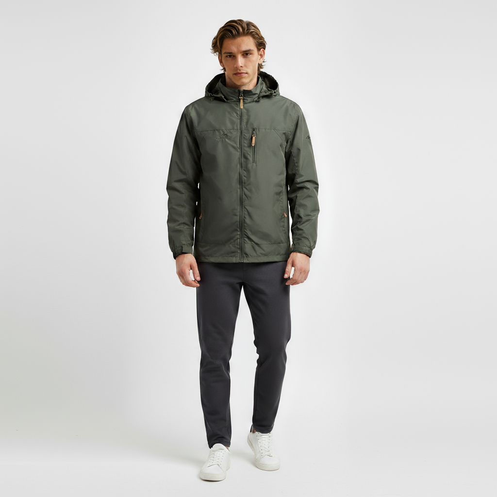 Mand iført grøn jakke og grå bukser, står mod hvid baggrund. Mode, herretøj, casual stil, moderne jakke, komfortable bukser, stilfuldt look.