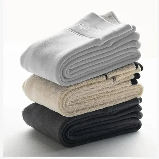 Stablede håndklæder i hvid, beige og grå på en hvid baggrund. Bløde, absorberende bomuldshåndklæder til badeværelse eller spa.