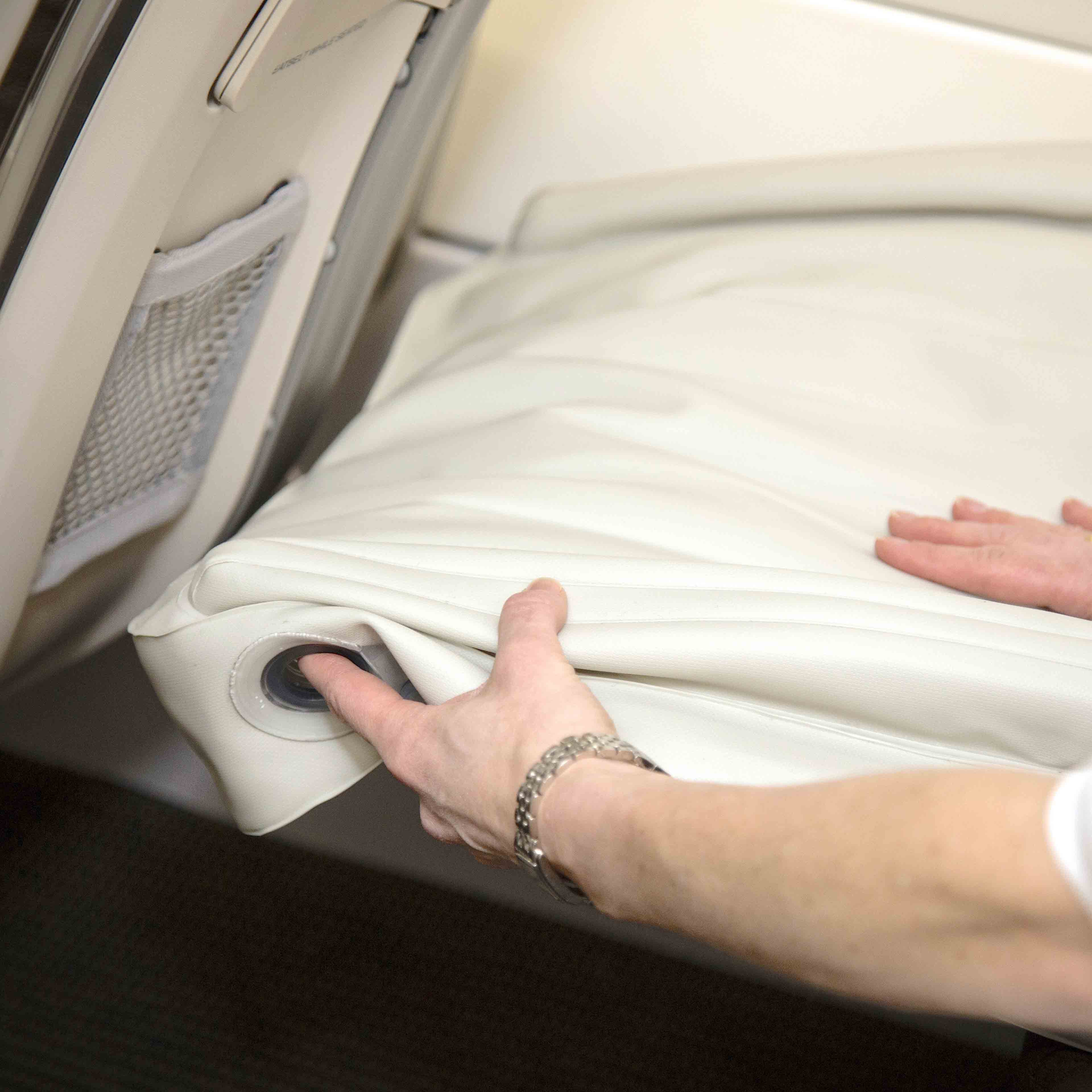 Person justerer hvidt lædersæde i bilinteriør. Fokus på håndtering af luksuriøst bilsæde, komfortabelt design, premium materialer.