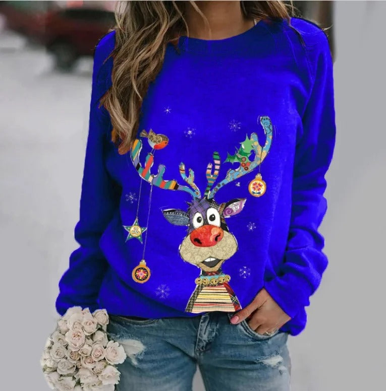 Kvinde i blå sweater med farverigt rensdyrmotiv, holder en buket hvide blomster. Perfekt til julemode, vintertøj, festlig stil.