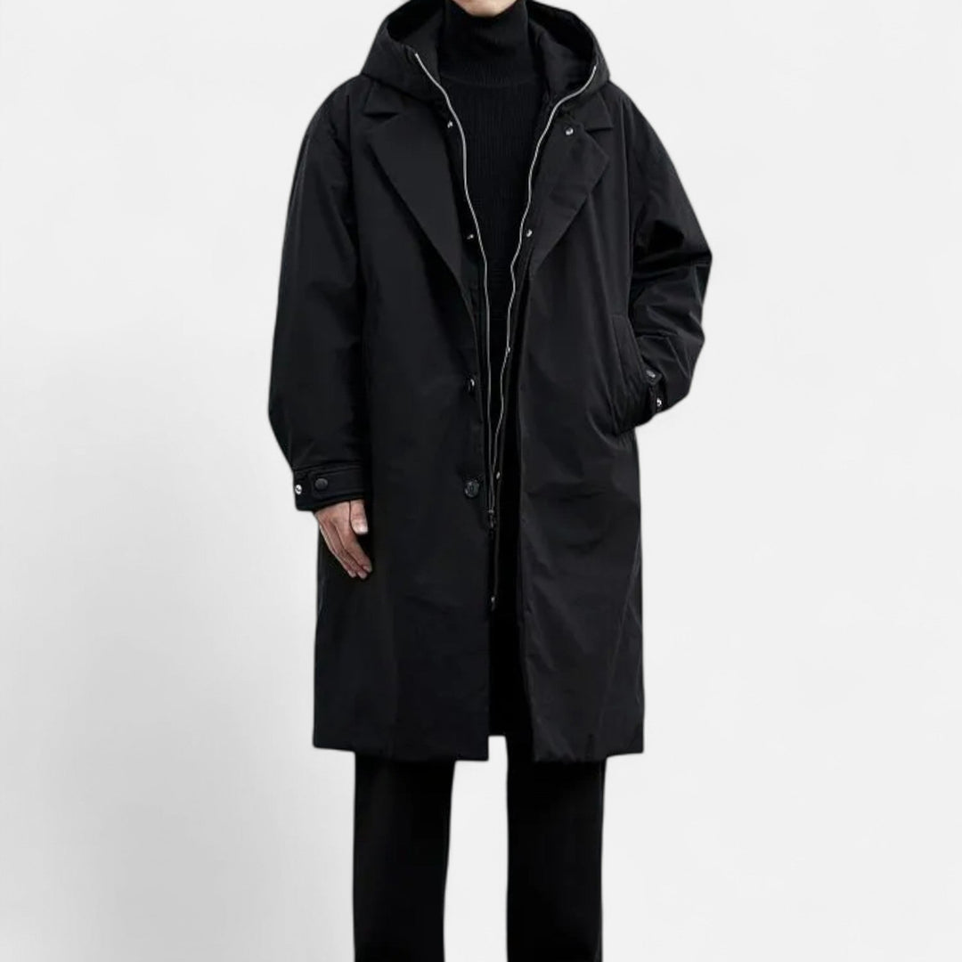 Sort frakke med hætte, knaplukning og sidelommer. Perfekt til vintermode og herretøj. Stilfuld og funktionel beklædning til koldt vejr.