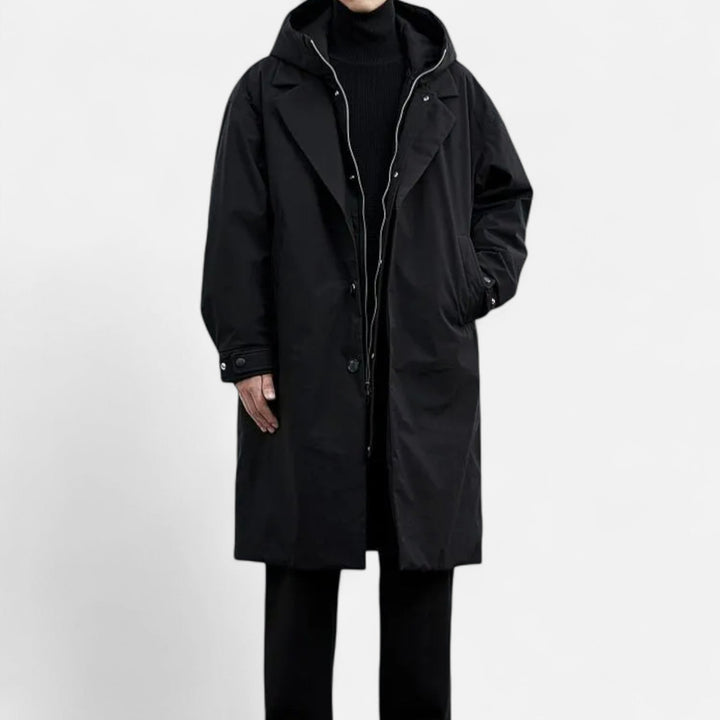 Sort frakke med hætte, knaplukning og sidelommer. Perfekt til vintermode og herretøj. Stilfuld og funktionel beklædning til koldt vejr.