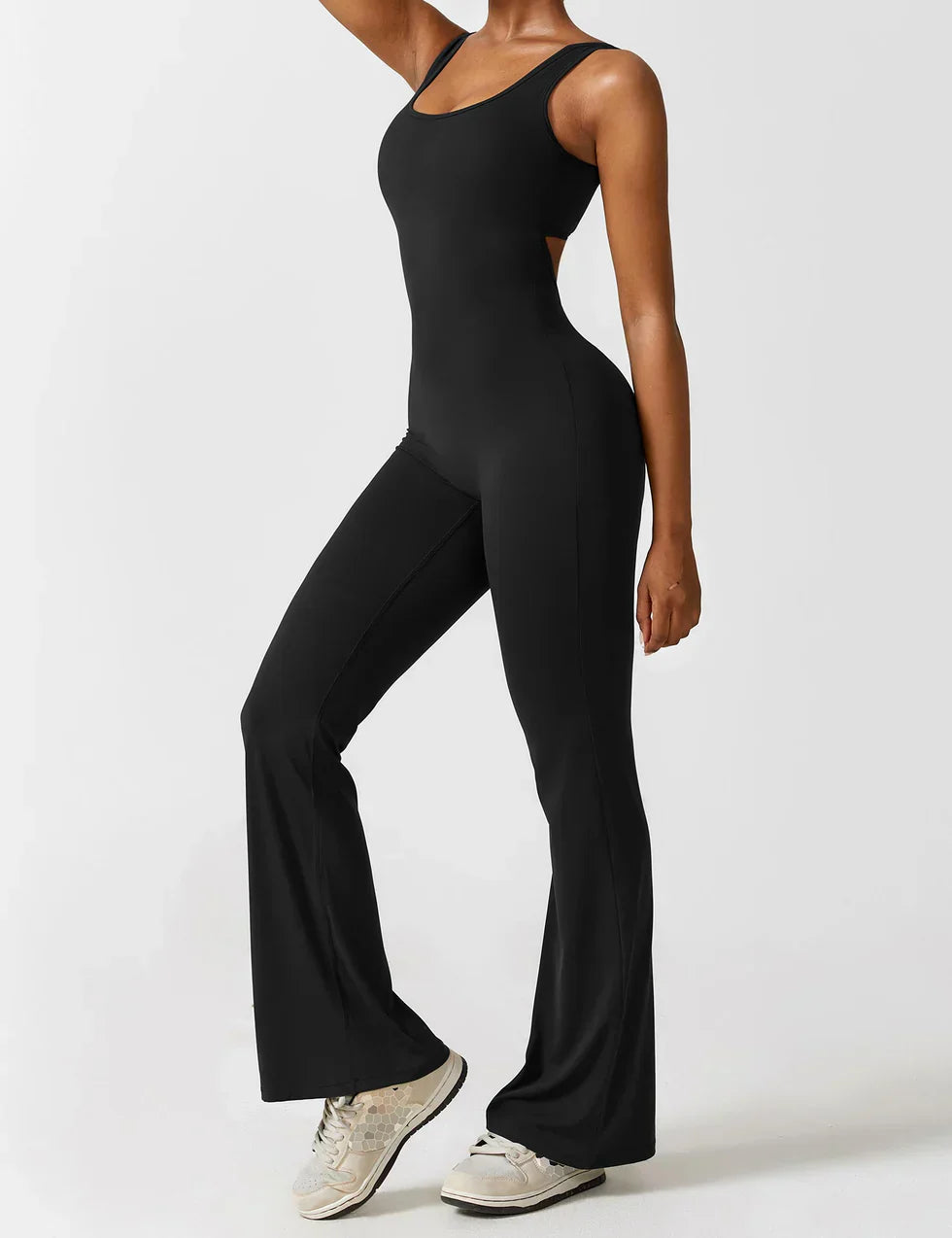 Sort fitness jumpsuit til kvinder, tætsiddende design med brede ben, bæres af model. Perfekt til yoga, træning og aktiv livsstil.