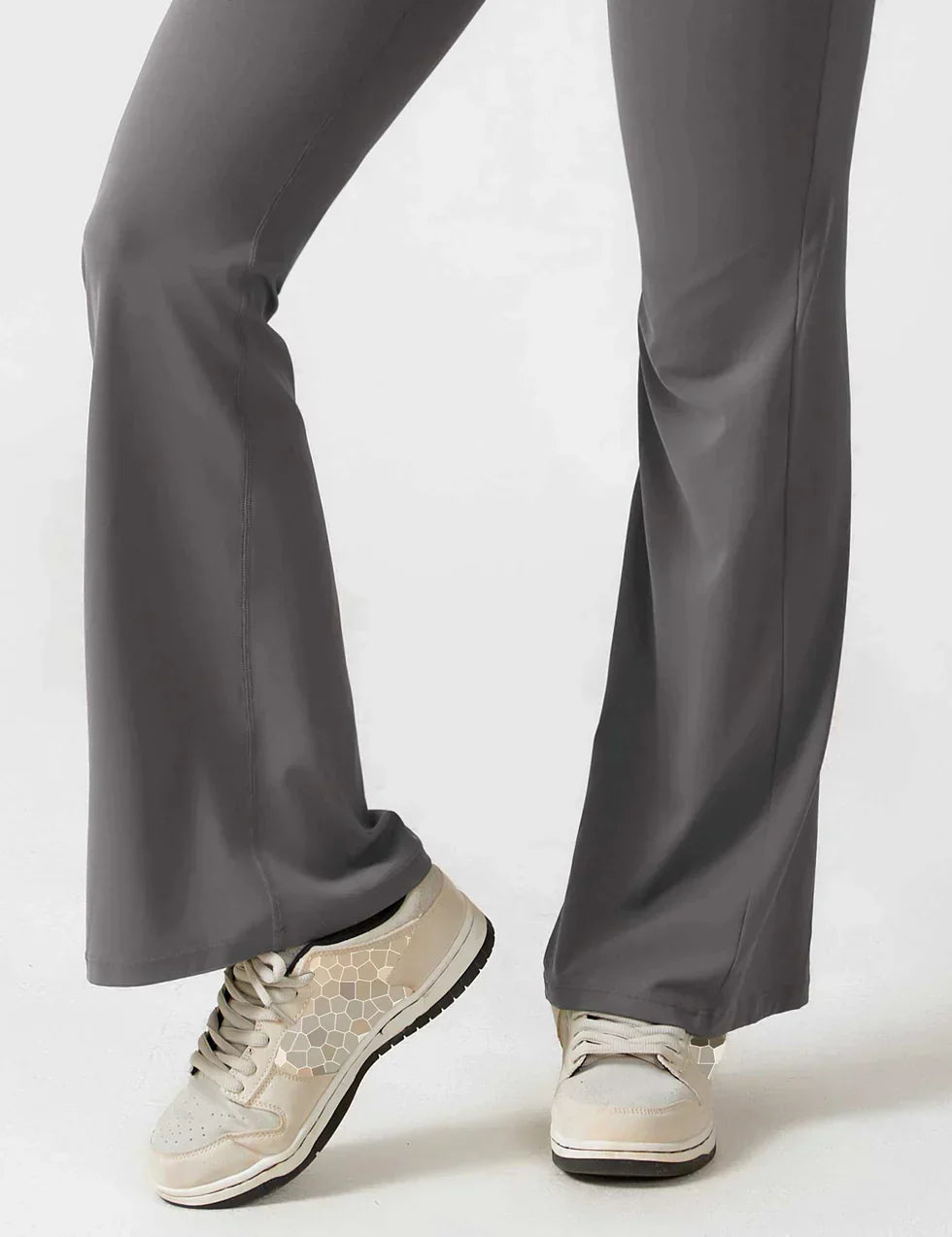 Grå bukser med vidde og hvide sneakers med sort sål. Komfortabelt og stilfuldt outfit til hverdagsbrug.