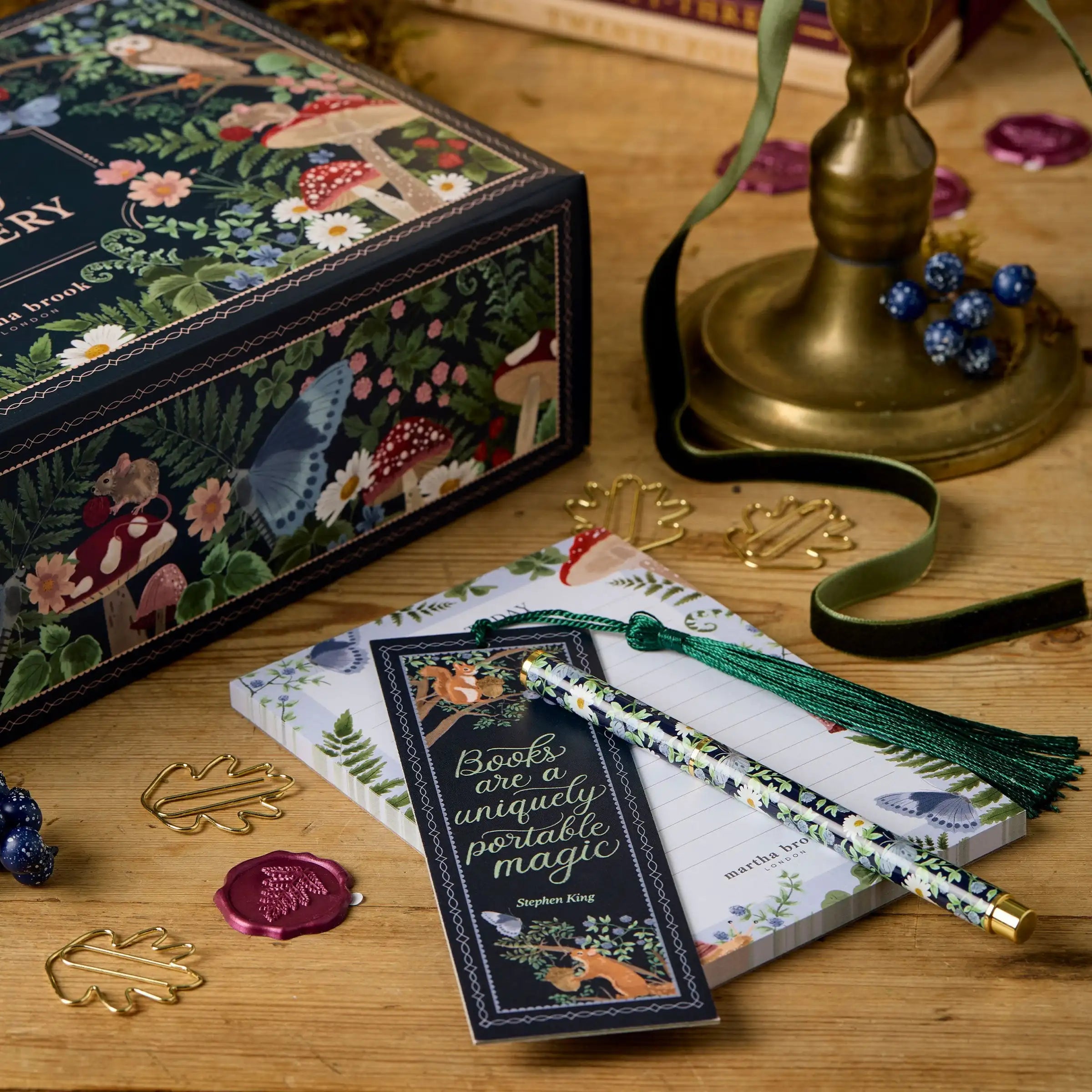 Bogtema gaveæske med notesblok, bogmærke og blyant på træbord. Dekoreret med skovmotiver, svampe og bær. Perfekt til bogelskere og skribenter.