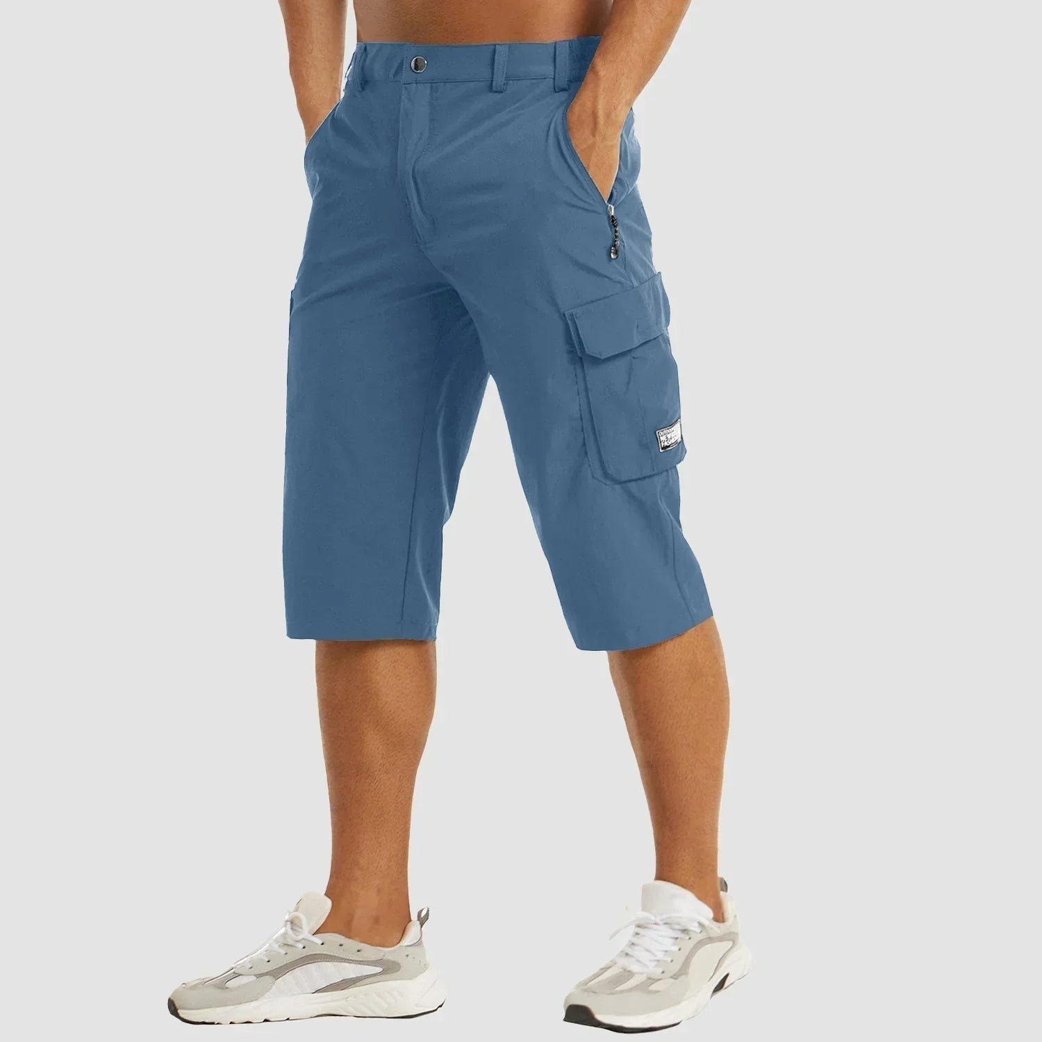 Blå cargo knickers til mænd med sidelommer, lynlåsdetaljer og knaplukning. Perfekt til casual sommerstil. Bæreren har hvide sneakers på.