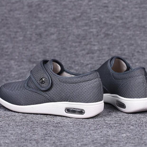 Grå ortopædiske sko med velcrolukning og hvid sål, designet til komfort og støtte, ideelle til daglig brug.
