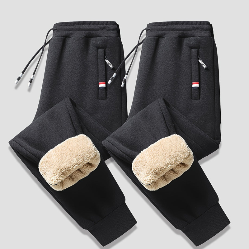 Sort fleeceforet joggingbukser til mænd med elastisk talje og snøre, to sidelommer med lynlås. Perfekt til vinter, komfort og stil.
