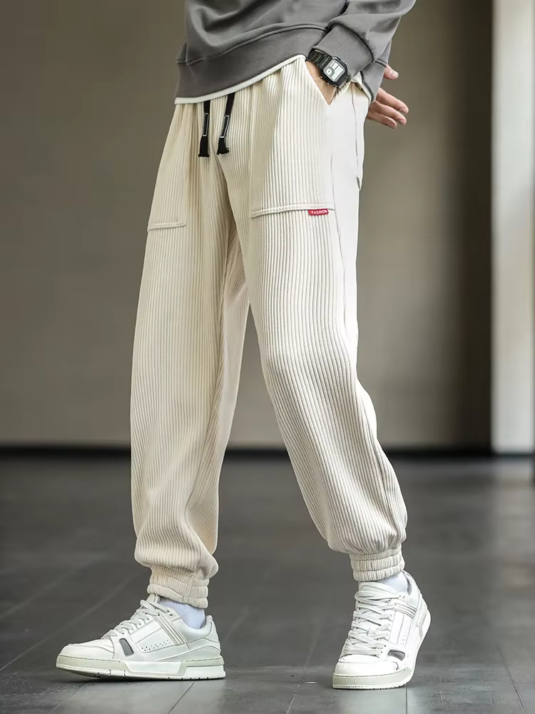 Beige ribbede joggers til mænd, kombineret med hvide sneakers. Moderne streetwear-stil, komfortabel pasform, ideel til afslappet mode.