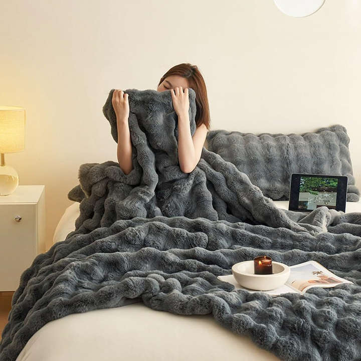 Kvinde med gråt, blødt tæppe på seng, moderne soveværelse, tændt stearinlys, tablet på natbord, hyggelig indretning, afslapning.