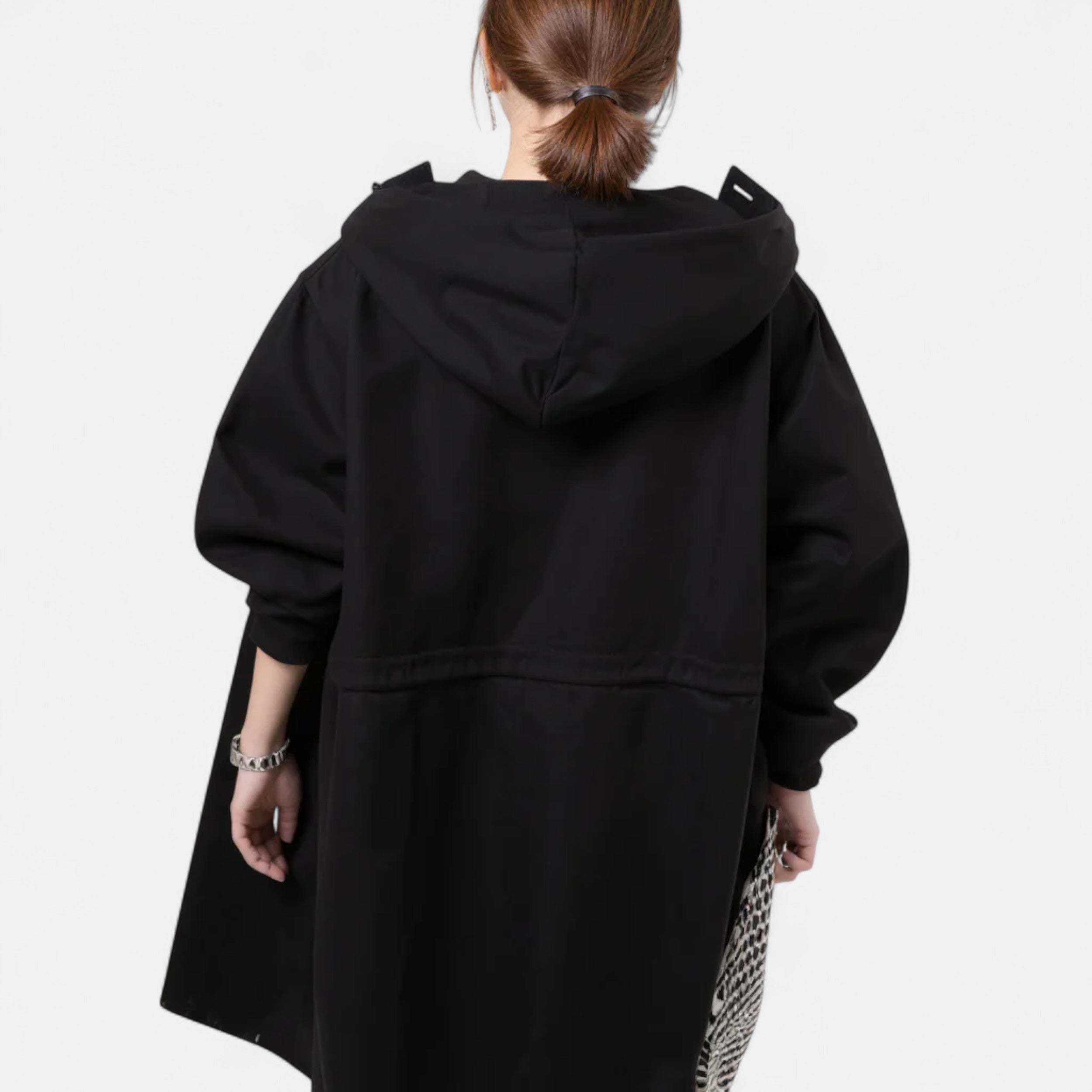 Kvinde iført sort hættetrøje set bagfra, minimalistisk design, trendy mode, urban stil, komfortabelt tøj, moderne kvindemode.