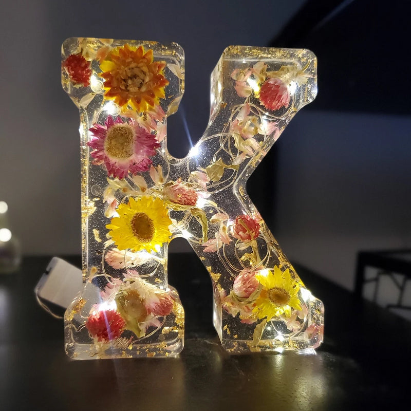 Dekorativt bogstav "K" med indlejrede tørrede blomster og LED-lys, perfekt til boligindretning. Unik gaveidé, der kombinerer natur og lysdesign.