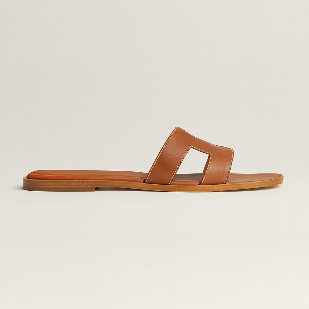Brun lædersandal med flad sål og åben tå, minimalistisk design. Perfekt til sommermode og afslappet stil. Komfortabel og stilfuld fodtøj.