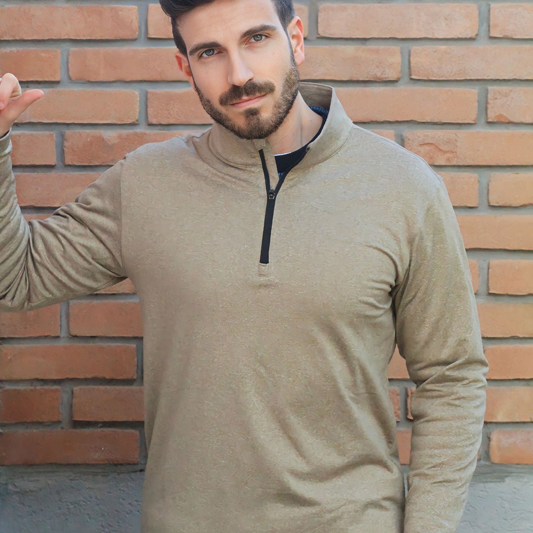 Mand iført beige trøje med lynlås foran murstensvæg. Moderne herremode, casual stil, langærmet trøje, trendy tøj til mænd.
