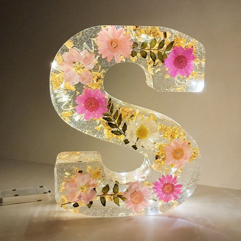 Dekorativt bogstav "S" i harpiks med indlejrede tørrede blomster og LED-lys. Perfekt til hjemmedekoration, unik gaveidé, blomsterkunst.