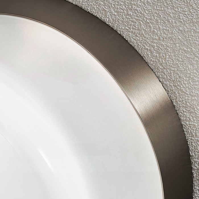 Moderne væglampe med hvidt glas og metalramme, monteret på struktureret væg. Stilfuldt belysningsdesign til indendørs brug.