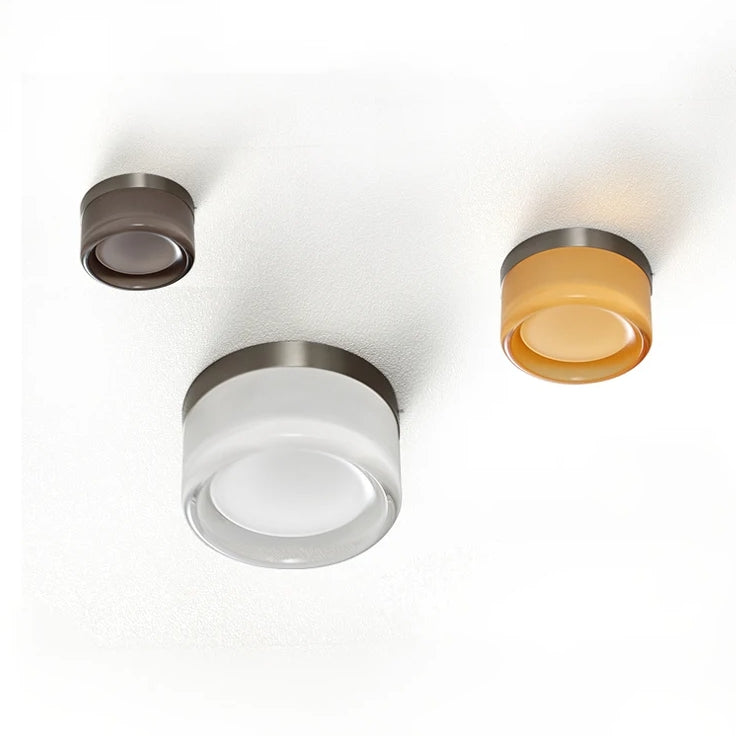 Tre moderne loftslamper i forskellige farver: brun, hvid og gul. Minimalistisk design, ideel til stilfuld belysning i hjemmet.