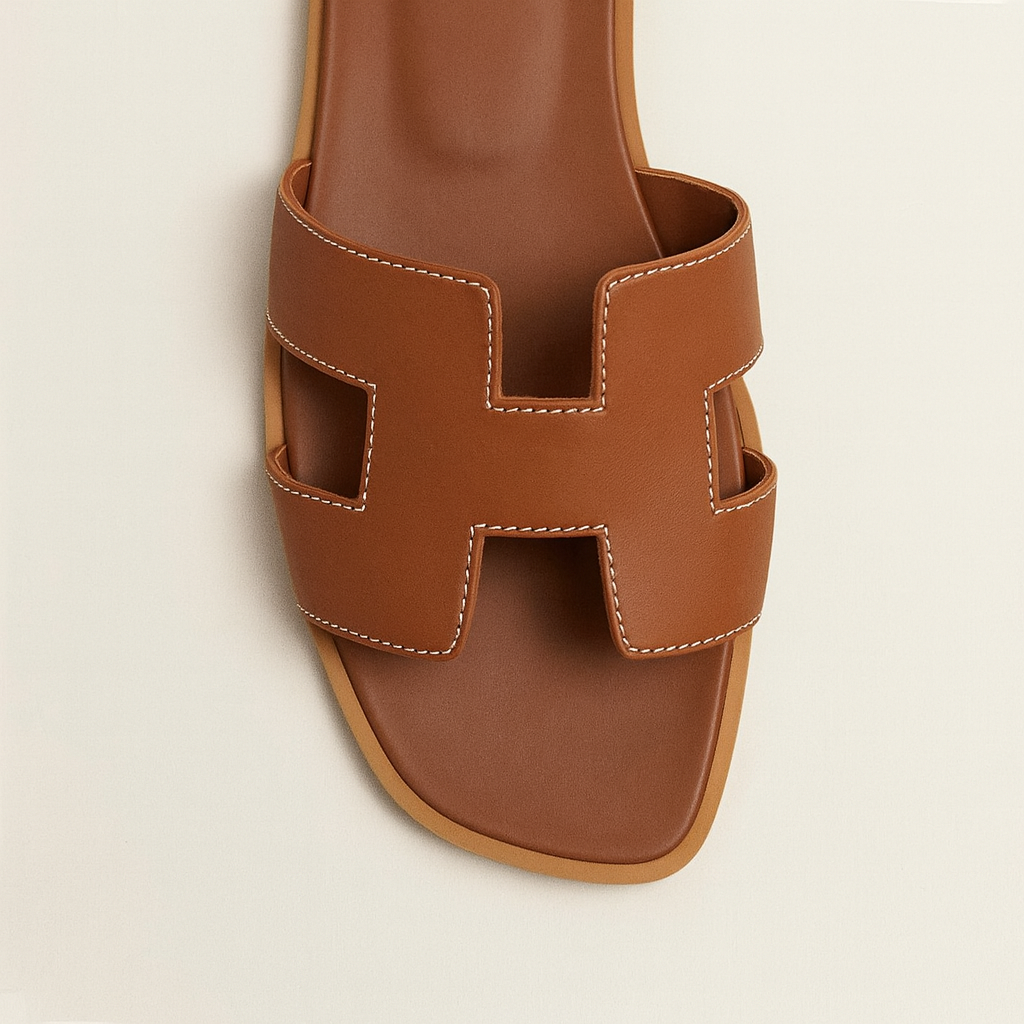 Brun lædersandal med H-formet rem, elegant design, perfekt til sommermode. Komfortabel og stilfuld fodtøj til kvinder.