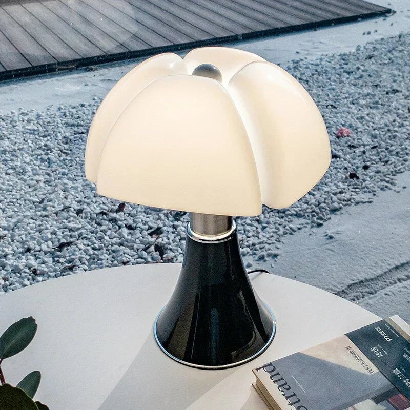 Moderne bordlampe med hvid blomstret skærm og sort base på bord ved siden af bøger. Stilfuld belysning til hjemmet, skandinavisk design.