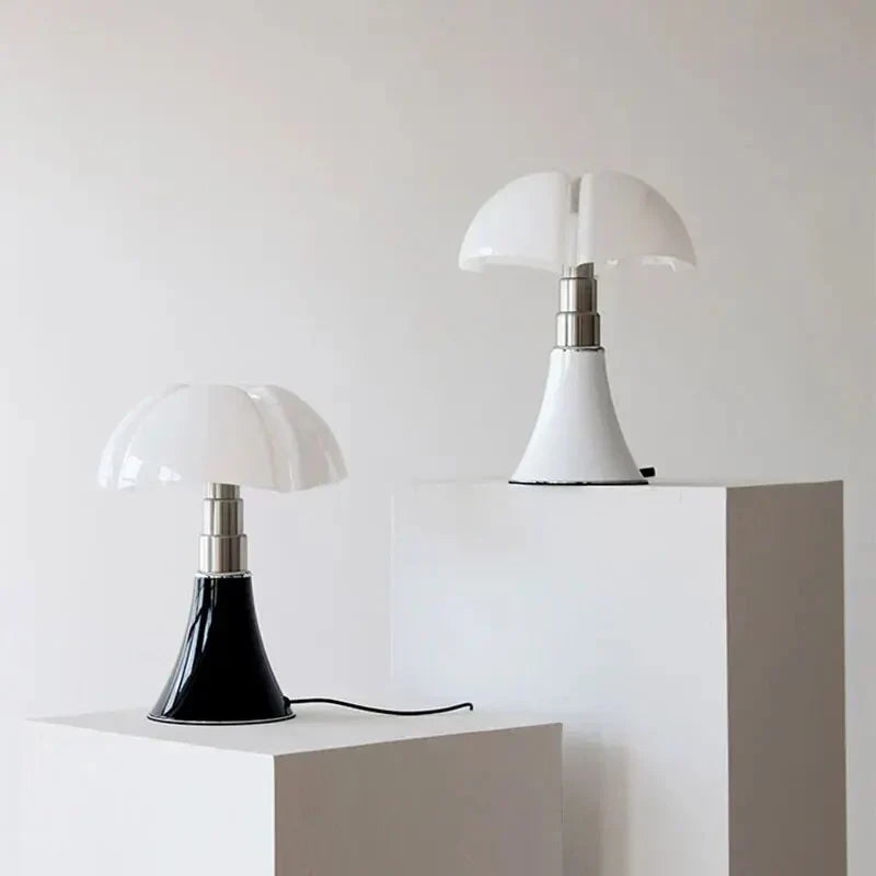 To moderne bordlamper med svampeformet design på hvide piedestaler, minimalistisk indretning, sort og hvid base, stilfuld belysning.